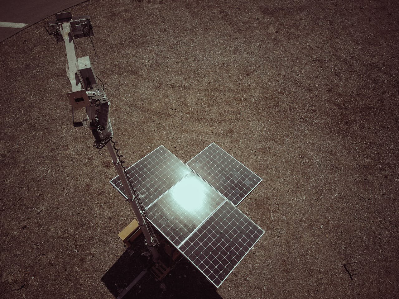 Aerial shot of a solar panel on a deserted landscape, reflecting sunlight.